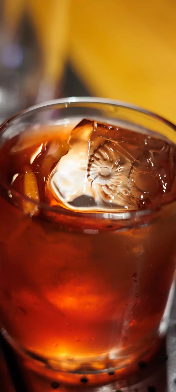 Foto bem próxima e detalhada de um drink do OIDĒ em copo de vidro. Na superfície um cubo de gelo com a gravação do símbolo do OIDĒ.