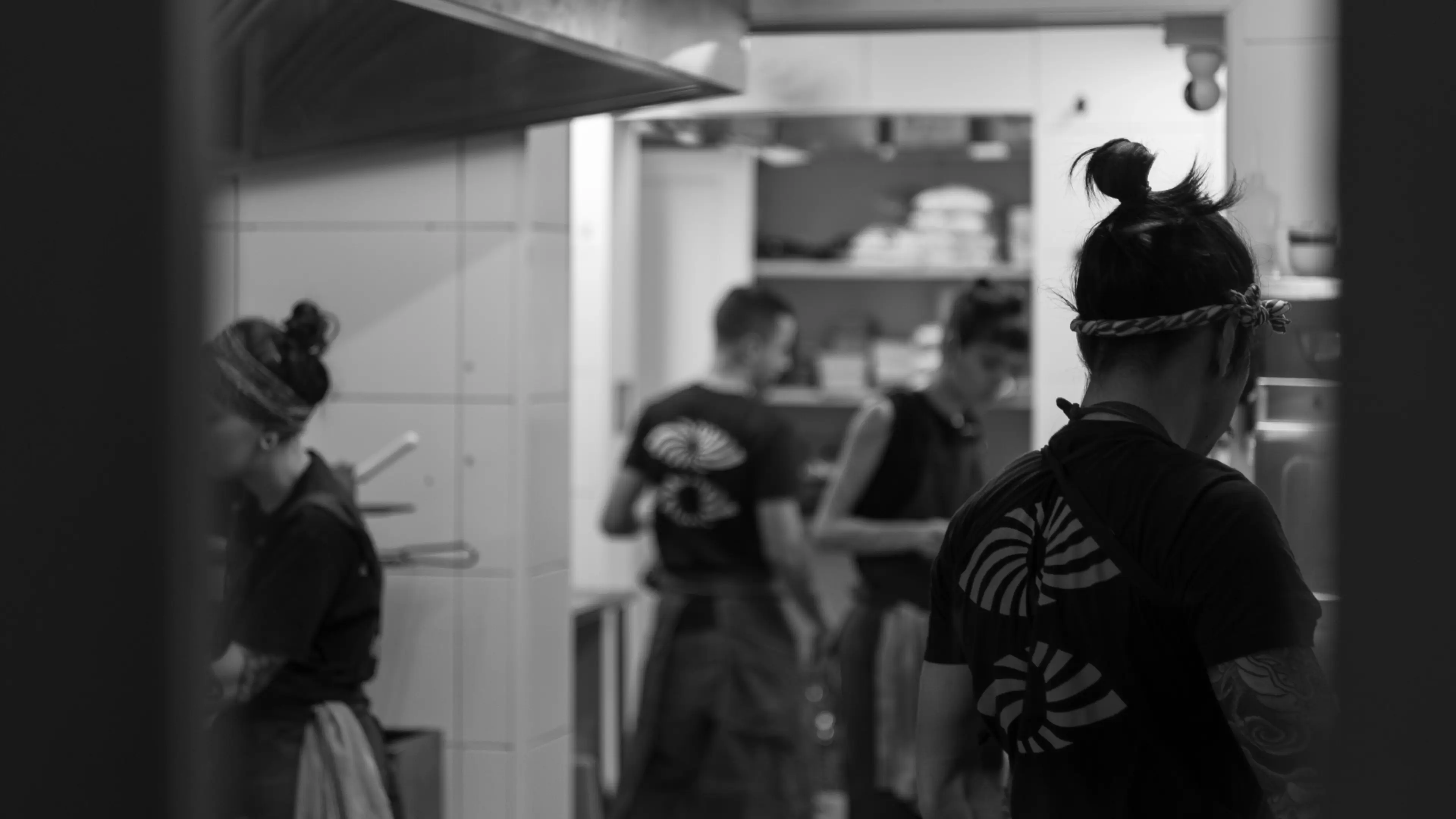 Foto em preto e branco da equipe de cozinha trabalhando.